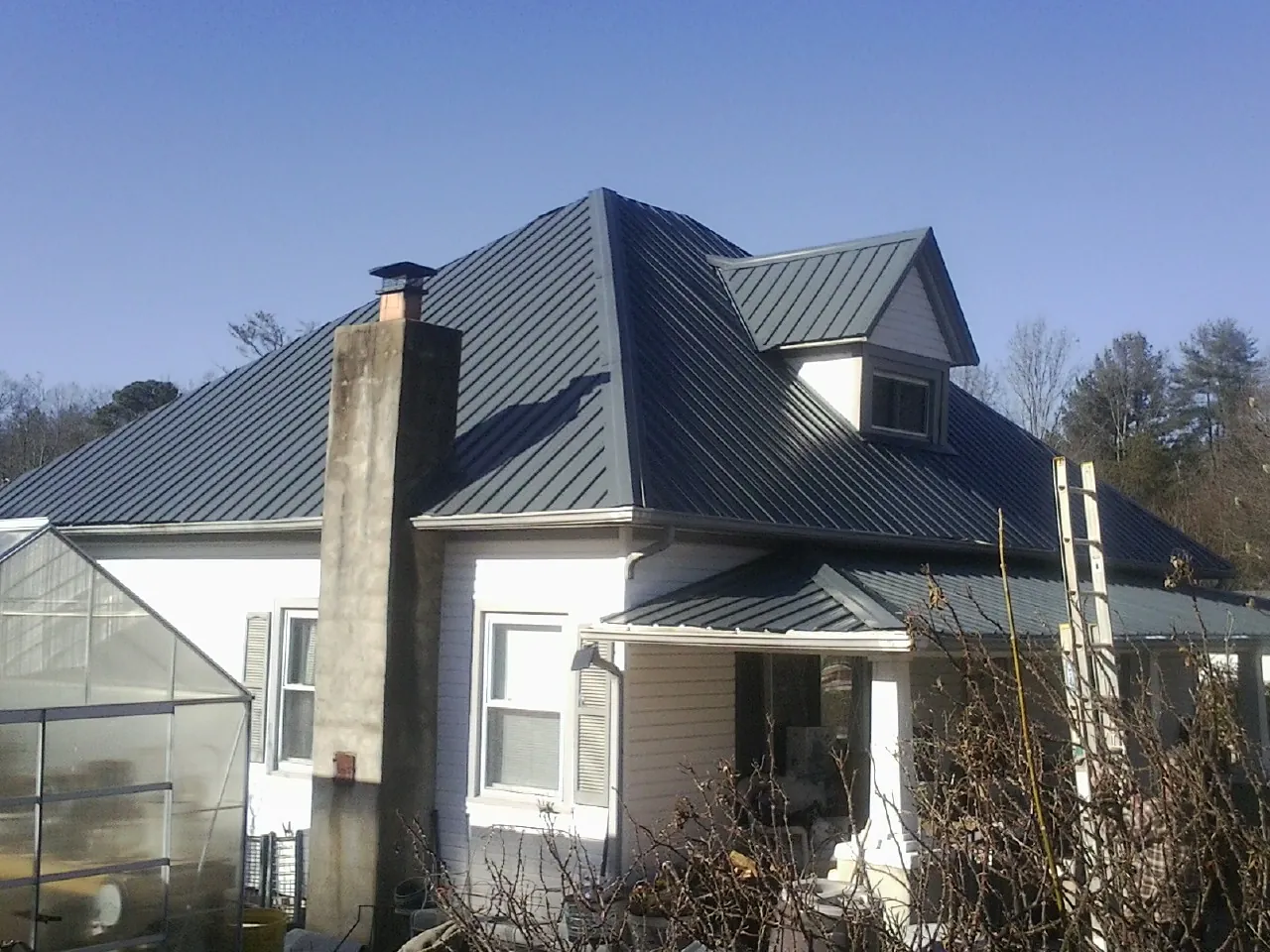 Dark blue standing seam metal roof on a white farmhouse with dormer — Slate & Tile Roof Repair by Roofing Brothers in Tahlequah