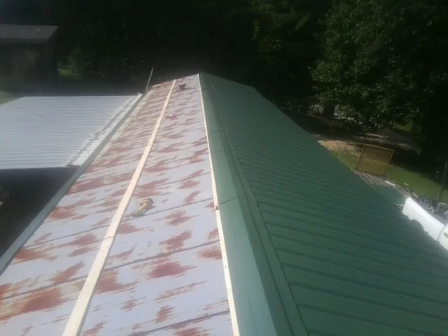 Old rusted panels beside newly installed green metal roofing — Wind Damage Roof Repair by Roofing Brothers in Tahlequah