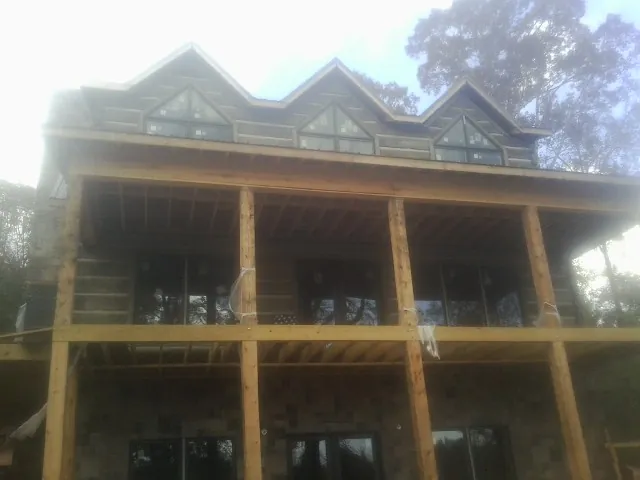 Dormers and porch framing on a large log home under construction — Roof Coating work by our crew in Tahlequah