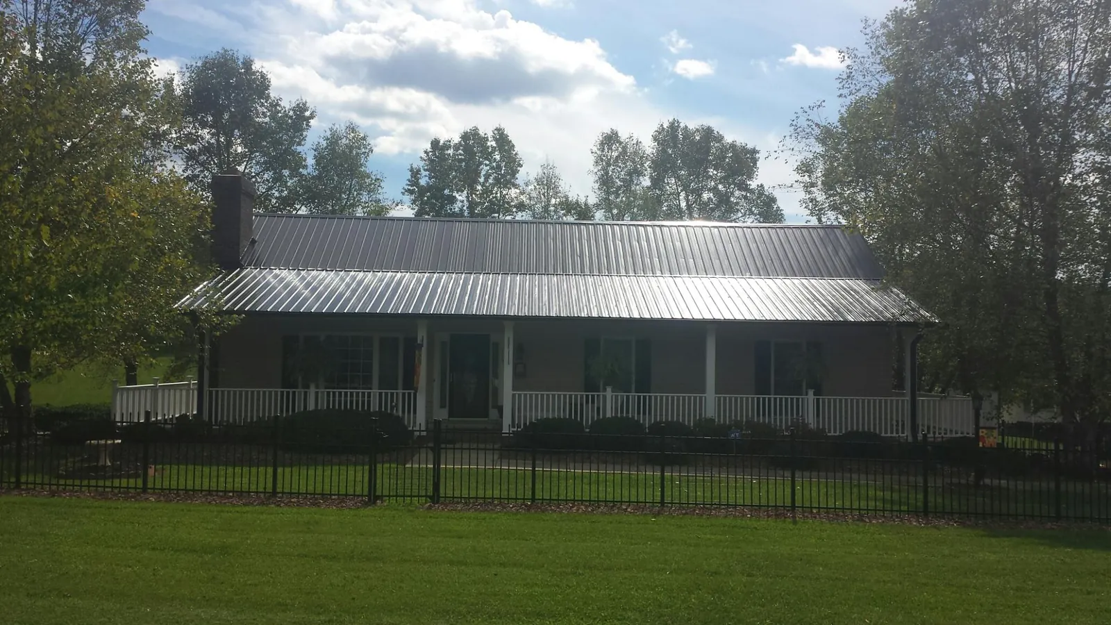 Gray metal roof on a brick ranch with a full width front porch — Gutter Guard Installation work by our crew in Tahlequah