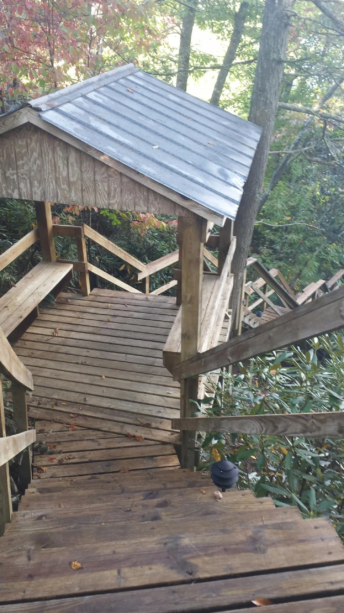 Metal roofed shelter over wooden steps on a wooded walkway — Skylight Repair & Installation work by our crew in Tahlequah