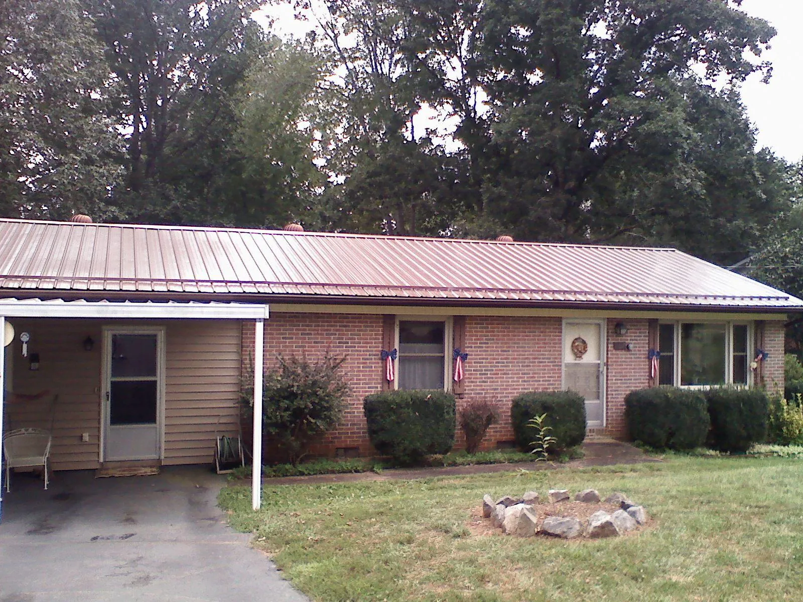 Bronze metal roof and carport on a brick ranch home — Roof Repair work by our crew in Tahlequah