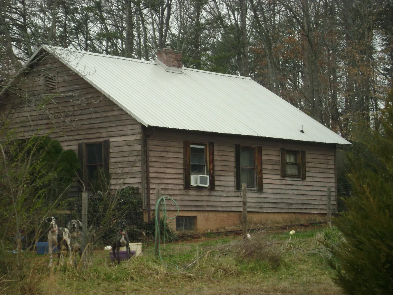 White metal roof on an old wood sided farmhouse, from a Asphalt Shingle Roof Repair job in Tahlequah
